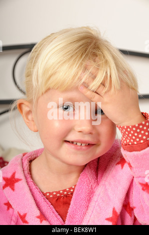 Stock photo d'une fillette de 4 ans en souriant tout en maintenant une part de sa tête. Banque D'Images