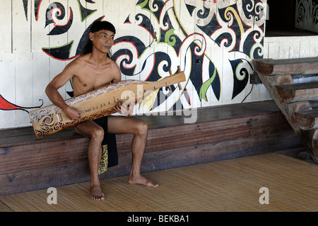 Homme ou musicien de la tribu Orang Ulu Sarawakian Sape ou un jeu de guitare Longue Maison Village Culturel de Sarawak en Malaisie Bornéo Banque D'Images