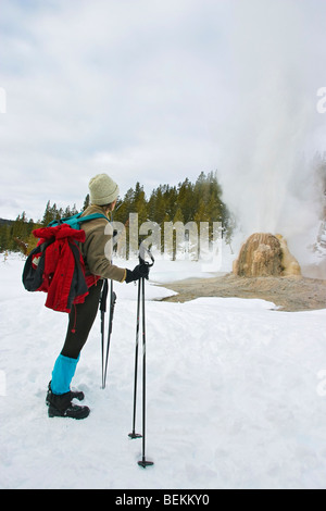 Ski de fond près de Lone Star Geyser comme elle éclate dans le Parc National de Yellowstone en hiver. Banque D'Images