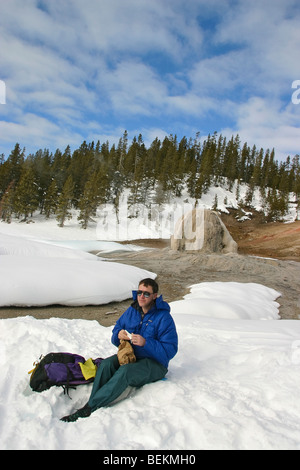 La fondeuse mange à midi près de Lone Star Geyser dans le Parc National de Yellowstone en hiver. Banque D'Images