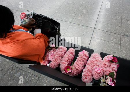 Siège passager d'une compagnie aérienne avec l'enterrement de la mère de fleurs dans le hall des départs de l'aéroport d'Heathrow Terminal 5. Banque D'Images