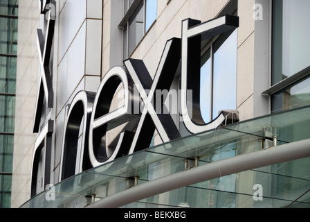 Close up of giant logo suivant affiche à l'extérieur de leur magasin à l'Arndale Centre, Exchange Square, Manchester, Angleterre, RU Banque D'Images