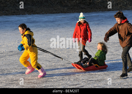 Enfant sur un traîneau et patineurs sur le canal gelé en hiver Banque D'Images