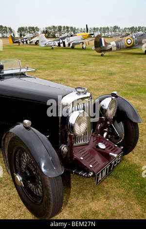 1934 Aston Martin Mk2 sur l'aérodrome à Goodwood Revival meeting, Sussex, UK. Mustang et Spitfire dans l'arrière-plan. Banque D'Images