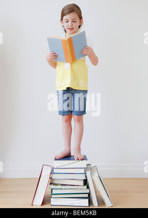 La lecture de l'enfant en étant debout sur les livres Banque D'Images