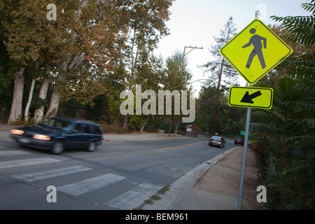 Une vue inclinée d'un piéton panneau routier et un tableau de concordance avec les voitures qui passent en début de soirée. Cupertino, Californie, USA Banque D'Images