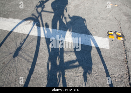 L'ombre portée de l'un cycliste qui tombe sur la route. Les cyclistes est l'exercice en cours les sacoches à la roue arrière. Banque D'Images