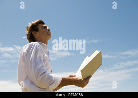 L'homme à l'extérieur avec livre ouvert, à la recherche de ciel était à Banque D'Images