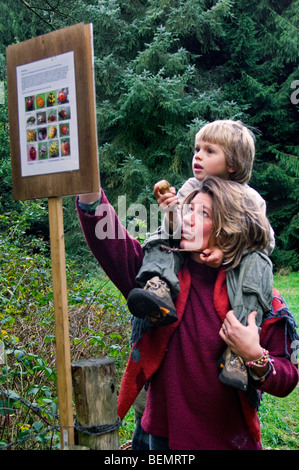 Mère portant sur les épaules de l'enfant l'apprentissage de la lecture par la nature de l'information de la faune le long du sentier pédagogique dans la forêt Banque D'Images