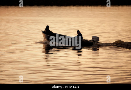 Pêcheurs se dirigeant vers la mer dans un petit bateau à moteur / skiff , Finlande Banque D'Images