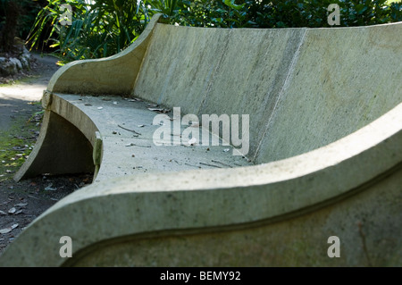 Banc de jardin en grès jonchée de feuilles d'automne et le feuillage et couverts de mousse vert et brun et les algues Banque D'Images