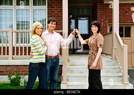 Couple heureux obtenir les clés de maison neuve d'agent immobilier Banque D'Images