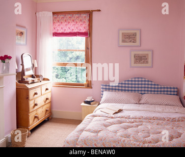 Aveugles et Rose rideau blanc sur la fenêtre en rose pastel pays chambre avec édredon rose sur lit avec tête de lit bleu vérifié Banque D'Images