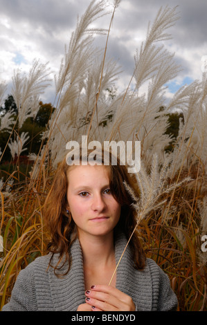 Young woman holding a tête de semences dans un grand stand de l'herbe de la Pampa sauvage à plumes blanches à l'automne Woodbridge Vaughan Ontario Canada Banque D'Images