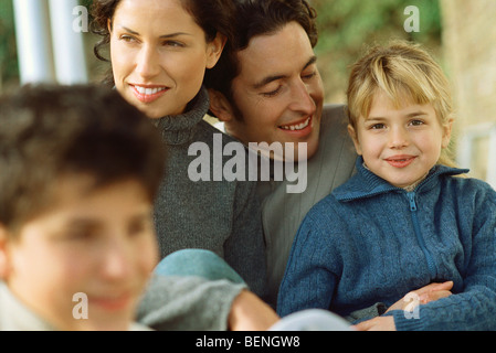 Petite fille assise avec les parents et le frère, smiling at camera Banque D'Images