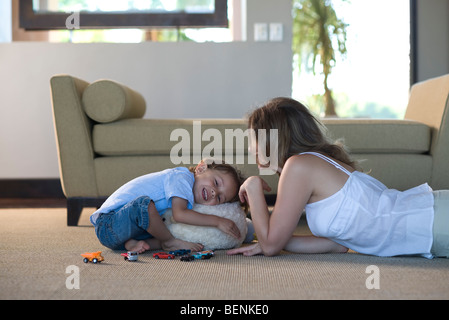 Mère et fils ensemble dans le salon de lecture, boy hugging stuffed toy Banque D'Images