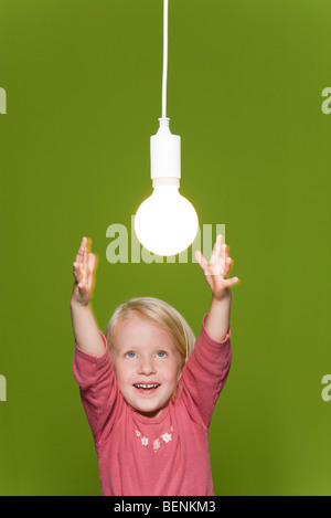 Petite fille d'atteindre pour la lampe suspendue Banque D'Images