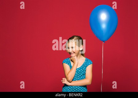 Fille avec la main sous le menton, derrière son ballon suspendu Banque D'Images