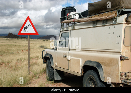 Off-road véhicule à quatre roues motrices et signe de la circulation sur la girafe savane, Namibie, Afrique du Sud Banque D'Images