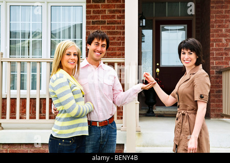 Couple heureux obtenir les clés de maison neuve d'agent immobilier Banque D'Images