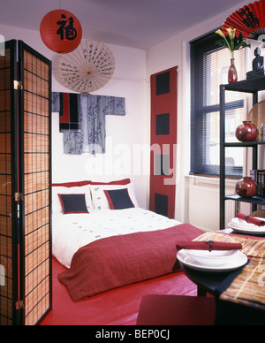 Kimono et parasol en papier sur le mur au-dessus de lit avec jet rouge dans un style oriental chambre moderne avec écran de bambou Banque D'Images