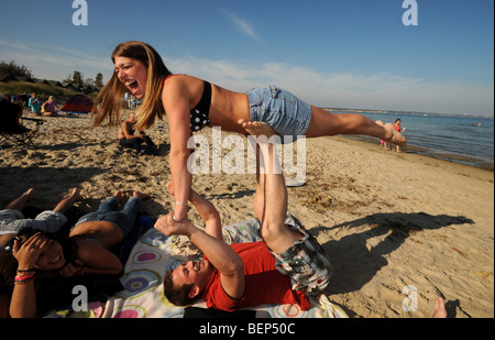 Un jeune homme et femme qui se trouvent également être frère et sœur jouant ensemble sur la belle plage de sable blanc Banque D'Images