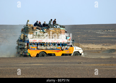 Bus très chargé avec les bagages et les passagers sur le toit de la conduite dans le désert du Sahara au Soudan, en Afrique du Nord Banque D'Images