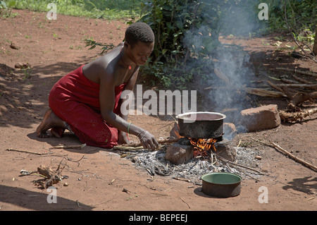 L'Ouganda, une jeune femme Proscovia, la cuisson sur un feu ouvert en face de sa petite chambre. Kayunga District. PHOTO par SEAN SPRAGUE Banque D'Images