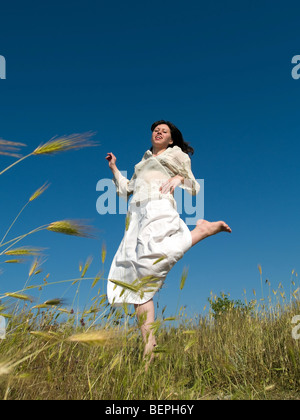 Jeune femme heureuse passe par sourire à l'appareil photo sur le terrain Banque D'Images