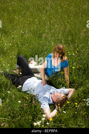 Homme, femme couchée dans l'herbe avec des fleurs Banque D'Images