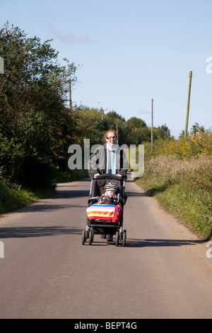 Mère poussant un petit garçon dans un pushcair, Hampshire en Angleterre. Banque D'Images