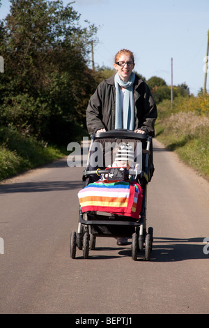 Mère poussant un petit garçon dans un pushcair, Hampshire en Angleterre. Banque D'Images