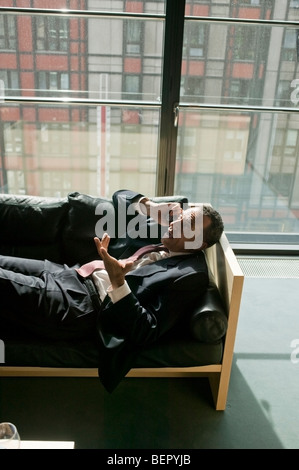 Man lying on sofa using cell phone Banque D'Images