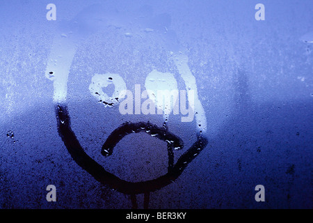 Un visage d'enfant malheureux sur la condensation sur les fenêtres. Banque D'Images