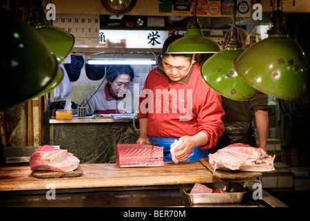 Un homme la préparation de thon frais en vente au marché aux poissons de Tsukiji à Tokyo Banque D'Images