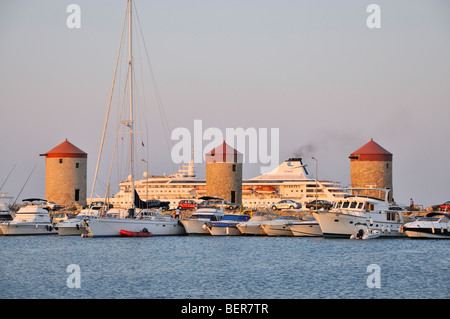 La ville de Rhodes, Grèce, vieux moulins, yachts, bateaux de croisière à voile et à la fin de l'après-midi la lumière à port de Mandraki. Banque D'Images