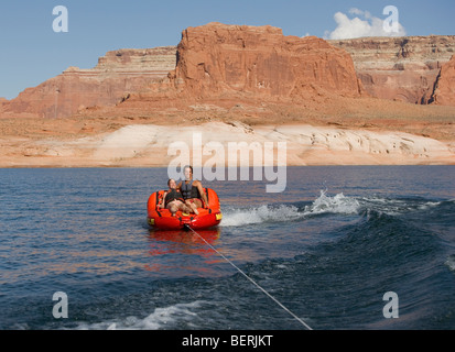 Un couple roule sur une remorque gonflable alors qu'il était remorqué par un bateau sur le lac Powell en Utah, USA. Banque D'Images