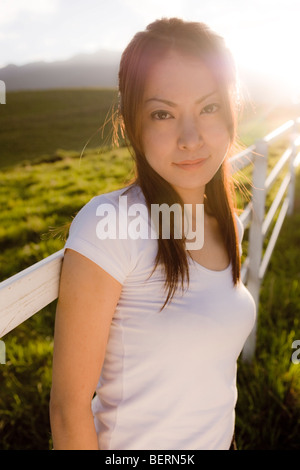 Portrait of young woman leaning on fence, looking at camera, Tochigi Prefecture, Japan Banque D'Images