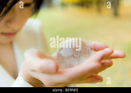 Young woman holding globe dans les mains, Close up Banque D'Images