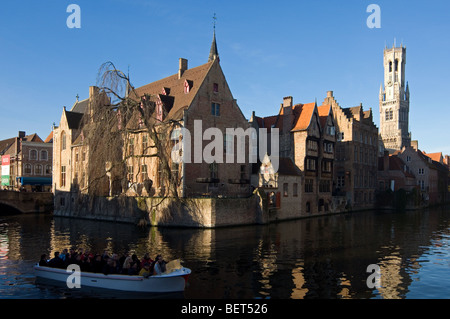 Beffroi et les touristes de prendre un tour en bateau sur les canaux de Bruges, Flandre occidentale, Belgique Banque D'Images