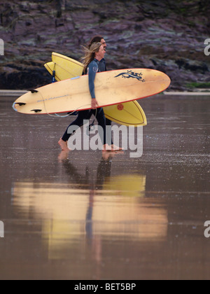 Deux surfeurs en direction de la mer avec la réflexion dans le sable humide. Banque D'Images