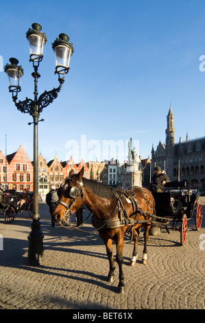 Façades colorées de restaurants et de l'entraîneur tirant avec les touristes sur la place du marché, Bruges, Flandre occidentale, Belgique Banque D'Images