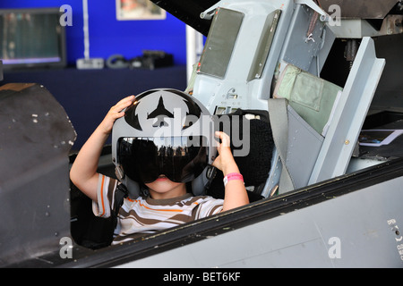 Dans le cockpit de l'enfant portant un casque de pilote de chasse à l'Airshow à Koksijde, Belgique Banque D'Images