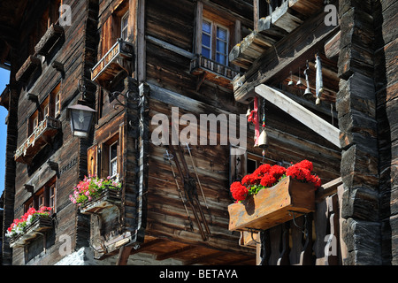 Avant de maison traditionnelle en bois décoré avec de vieux skis et de géraniums dans le village alpin de Grimentz, Valais, Suisse Banque D'Images