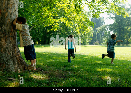 Trois enfants jouant à cache-cache dans le parc Banque D'Images