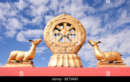 Les statues sur le toit haut de temple du Jokhang à Lhassa de deux golden deer flanquant une roue du Dharma. Banque D'Images