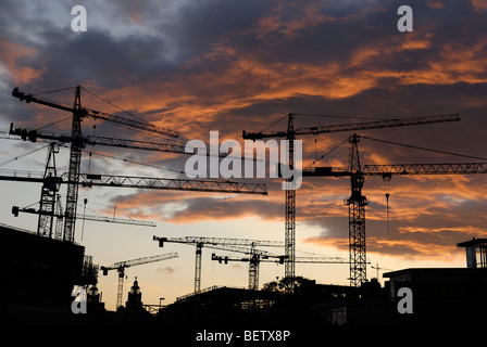 Grues de construction tour silhouetted against red sunset Banque D'Images