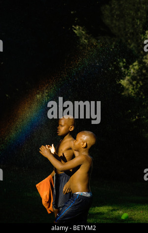 Deux garçons rester au frais sous une douche improvisée de l'eau sur une journée chaude sur un conseil estate dans le nord de Londres Banque D'Images