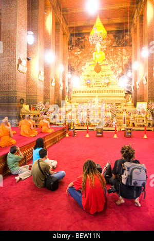 Un moine en prière à l'intérieur d'un temple de Wat Po complexe. Bangkok, Thaïlande Banque D'Images