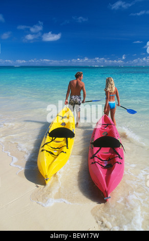 Couple avec kayaks entrant dans l'eau ; Plage Lanikai, Windward Oahu, Hawaï. Banque D'Images